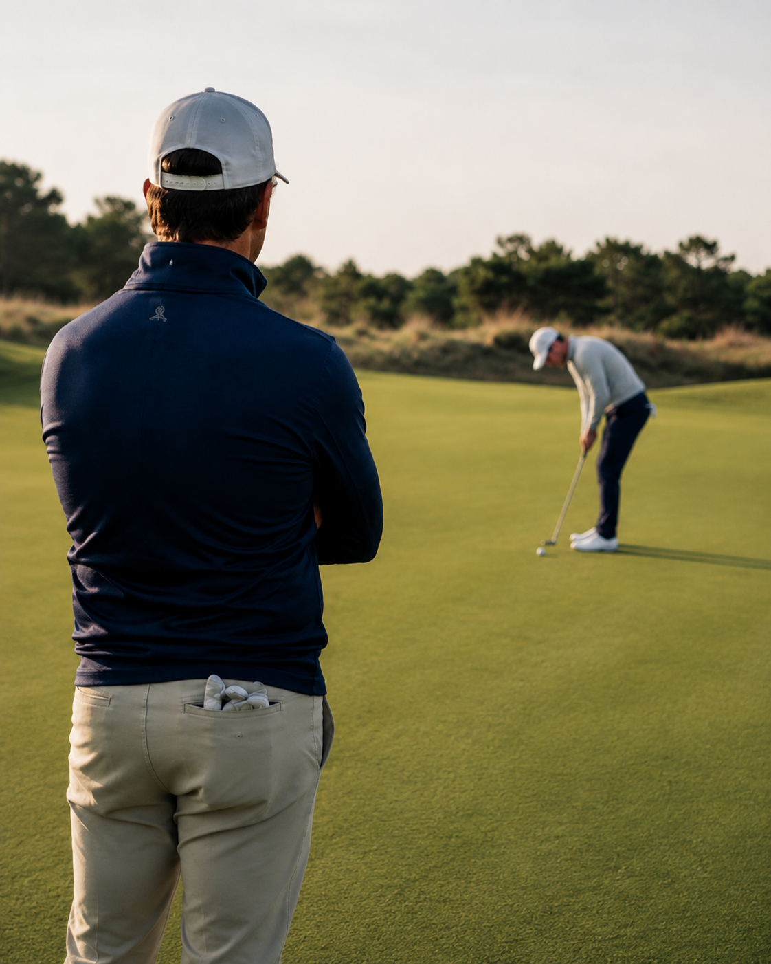 A teaching professional watching a golfer putt on the practice green